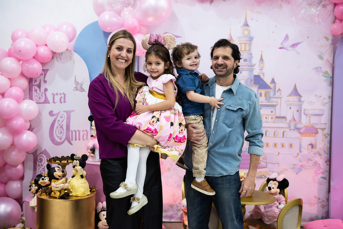 família feliz na frente do tema da Minnie rosa
