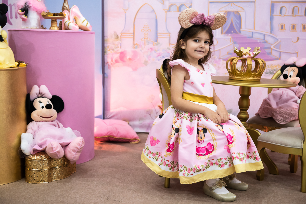 menina sentada na cadeira da mesa da Minnie