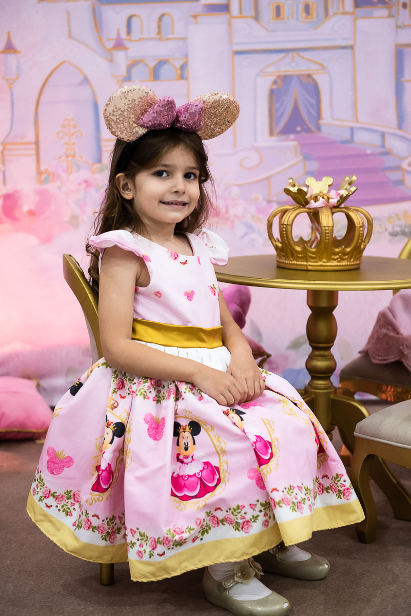 menina sorrindo sentada na cadeirinha da minnie