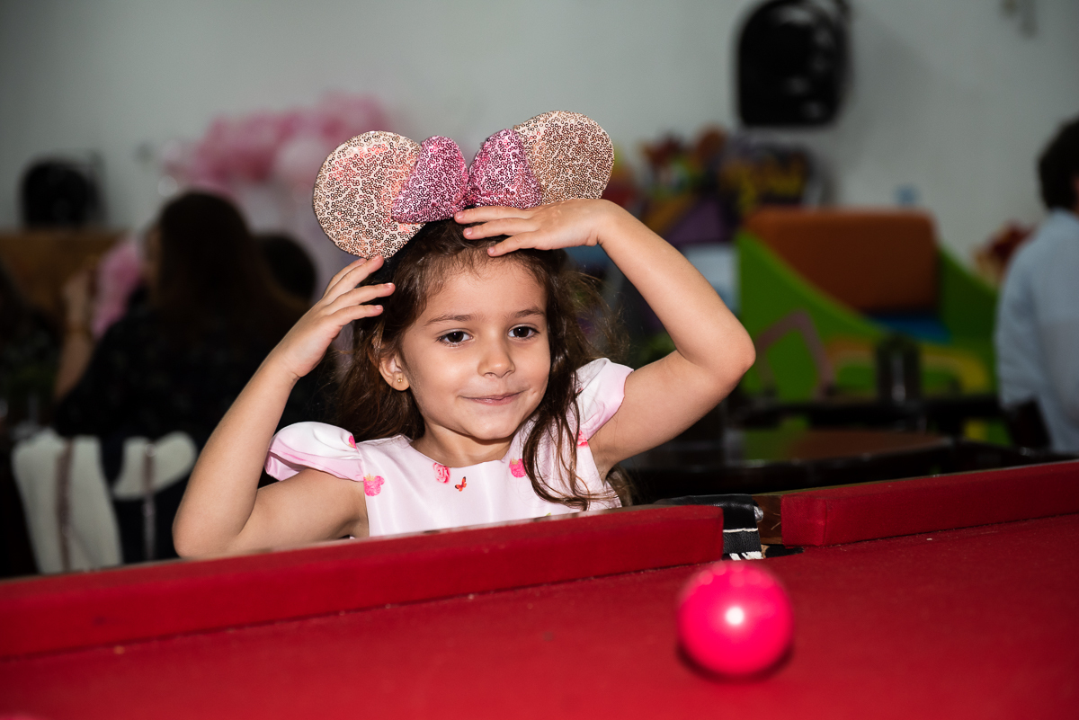 menina brincando na mesa com a bolinha rosa