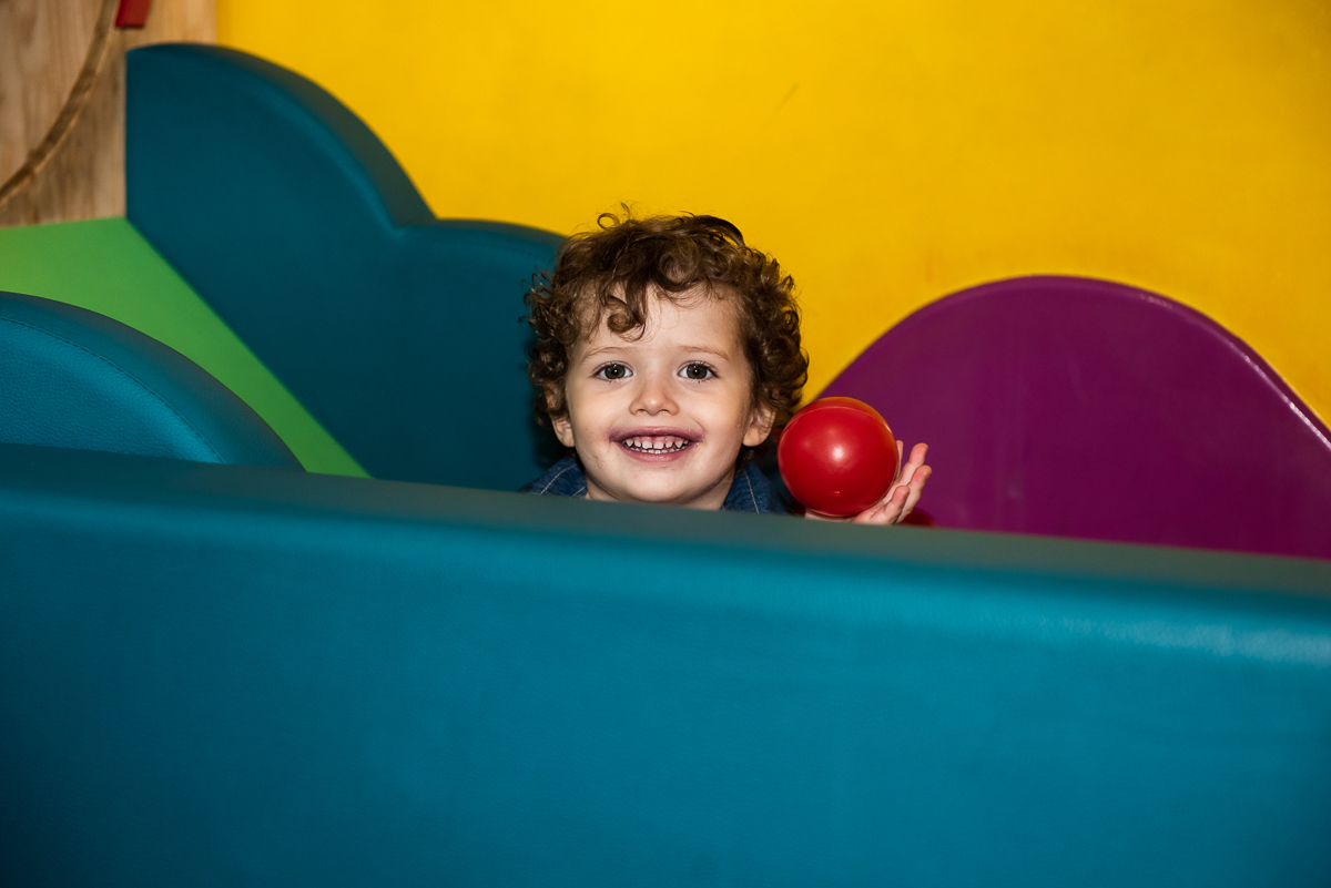 menino se divertindo com a bolinha vermelha na mão