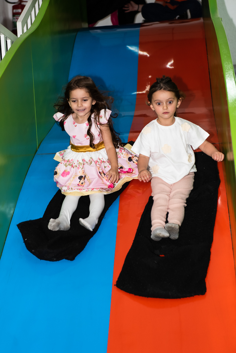 uma menina feliz, outra assustada, descendo o escorregador