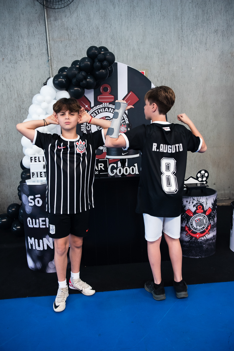 um menino de frente, outro de costa, com camisas do Corinthias