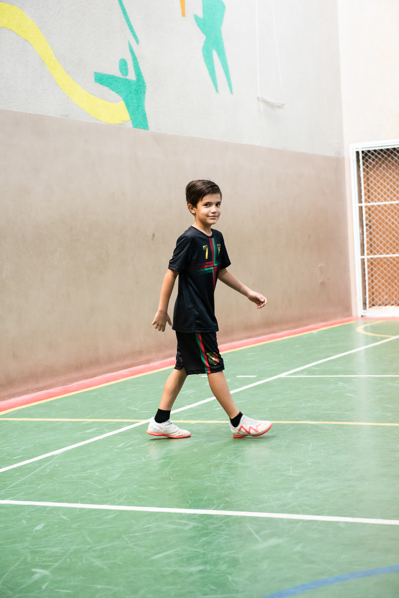 menino de uniforme preto passeando na quadra
