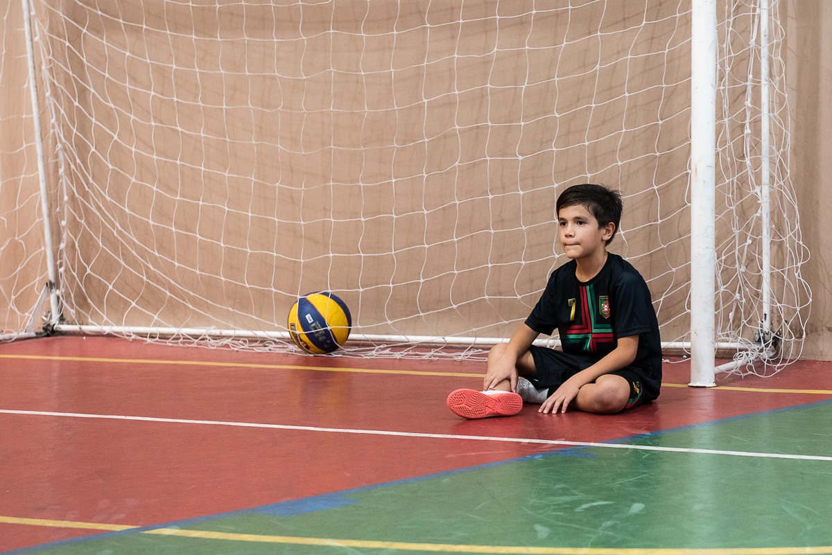 menino sentado na trave do gol