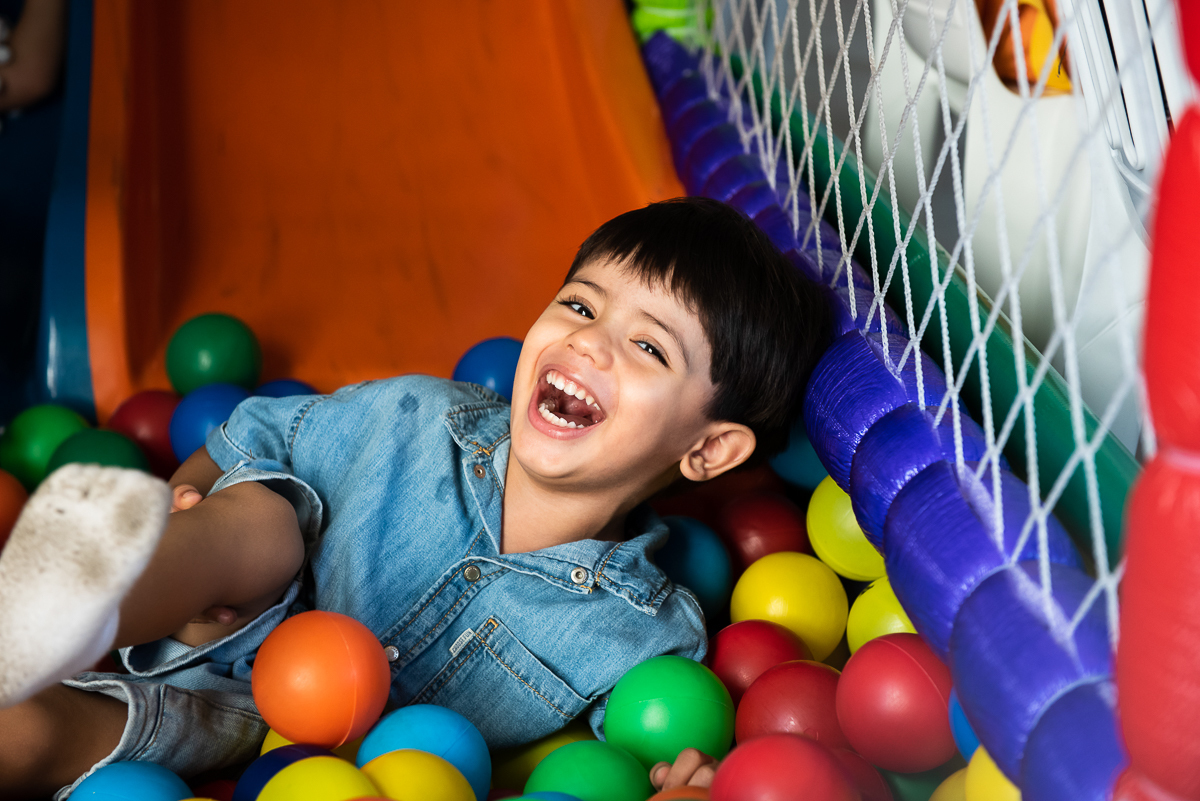 menino sorrindo na piscina de bolinha