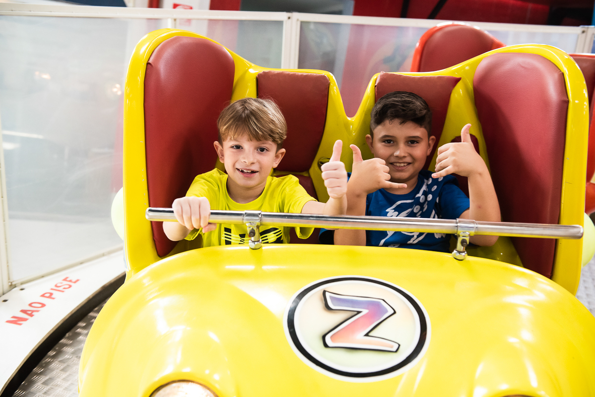 dois meninos brincando no carrinho amarelo