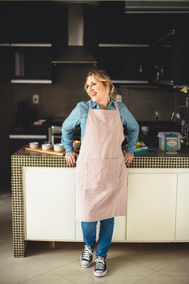 Ensaio de mulher empreendedora na gastronomia e confeitaria Mari Schiesari com jeans e avental rosa no Bairro Saúde em São Paulo com Dani Ortiz