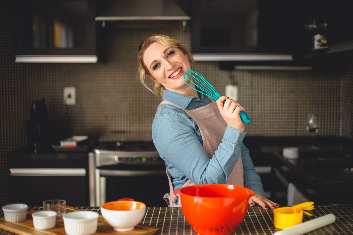 Ensaio de mulher empreendedora na gastronomia e confeitaria Mari Schiesari com jeans e avental rosa fazendo bolo no Bairro Saúde em São Paulo com Dani Ortiz