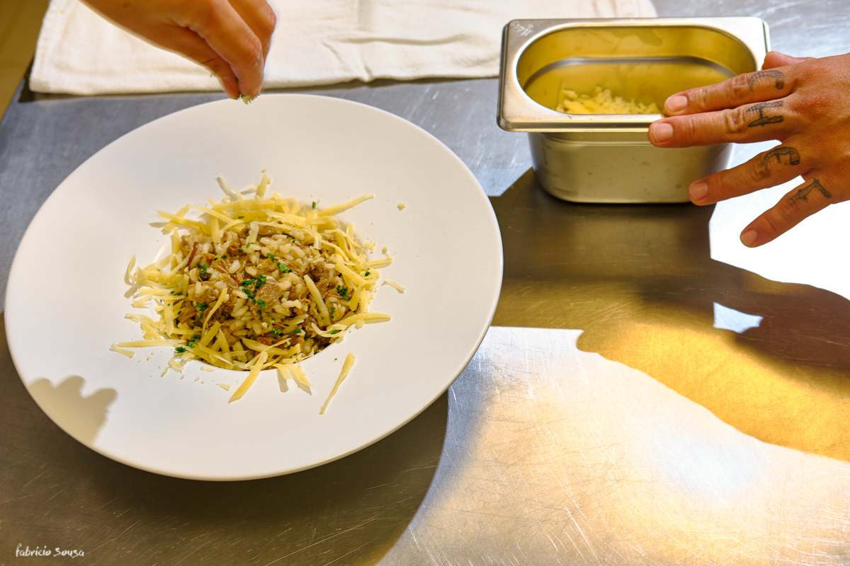 arroz de pato com toque de queijo ralado. detalhe da tatuagem chef de cozinha apaixonado pela profissão