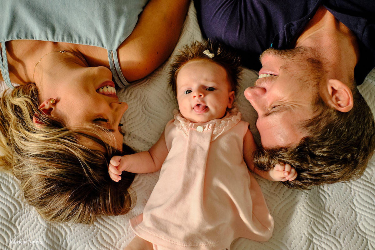 sessao de fotos com bebe em casa papais se divertindo na cama