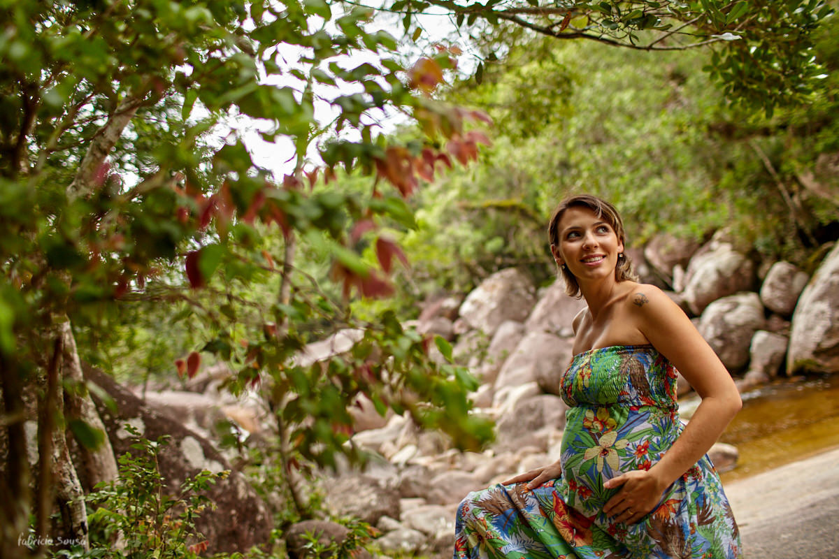 grávida Aline com vestido verde em meio a natureza no seu book gestante na cachoeira