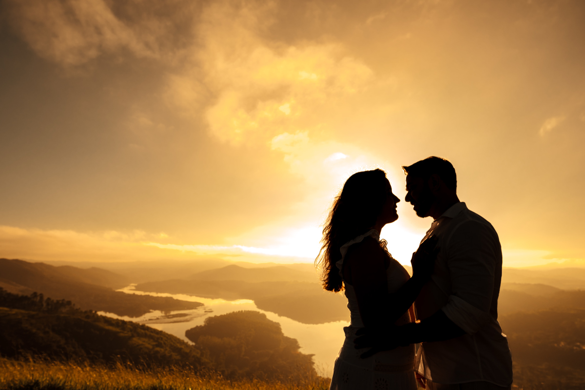 Ensaio pré-wedding romântico no campo, com casal trocando olhares apaixonados em meio à luz dourada da manhã