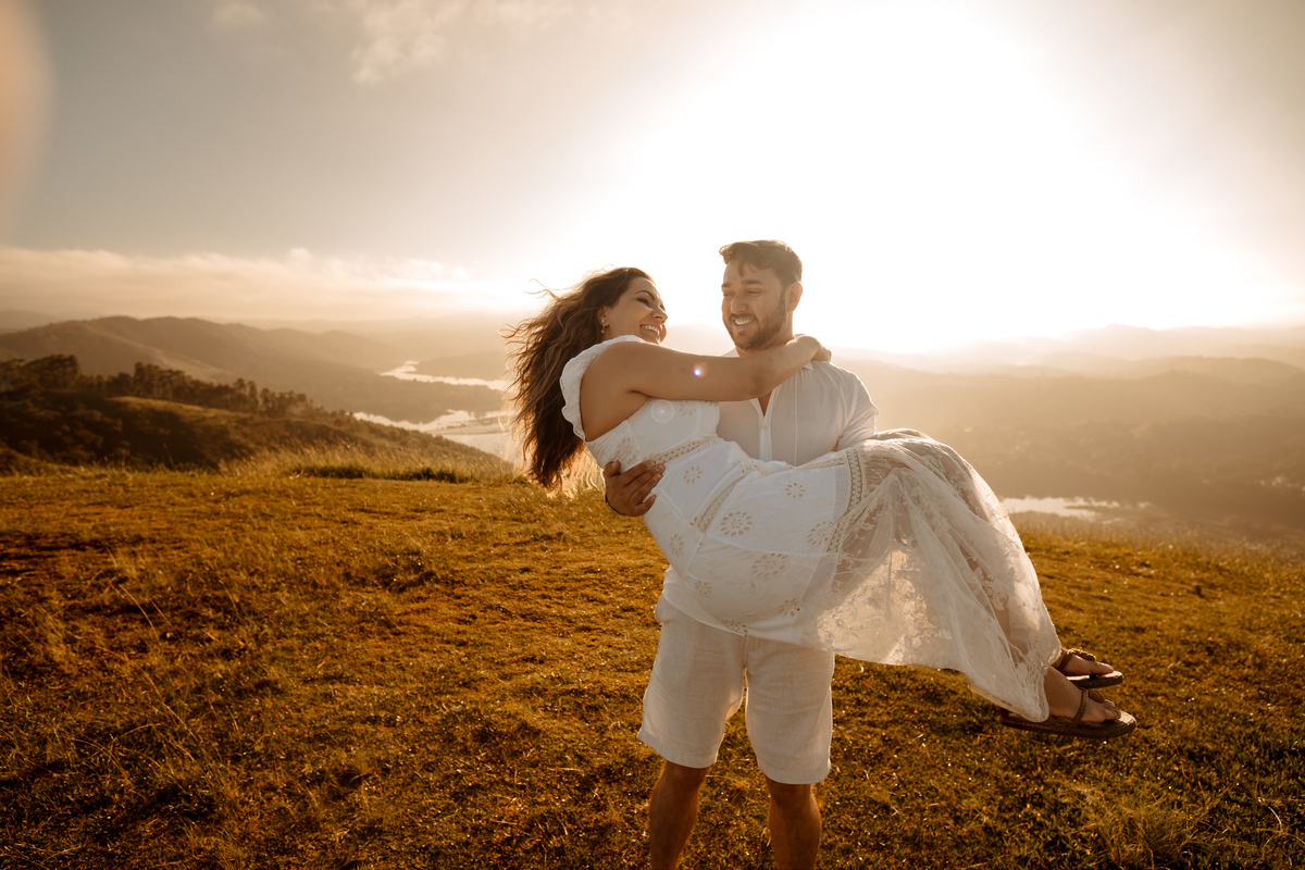Ensaio pré-wedding romântico no campo, com casal trocando olhares apaixonados em meio à luz dourada da manhã
