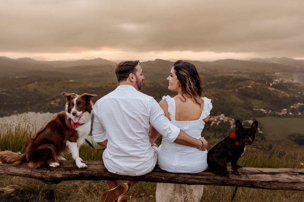Casal em ensaio pré-wedding ao nascer do sol no Morro do Capuava, rodeado pela natureza e acompanhados por seus cachorros