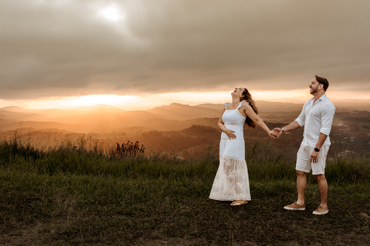Casal em ensaio pré-wedding ao nascer do sol no Morro do Capuava, rodeado pela natureza e acompanhados por seus cachorros