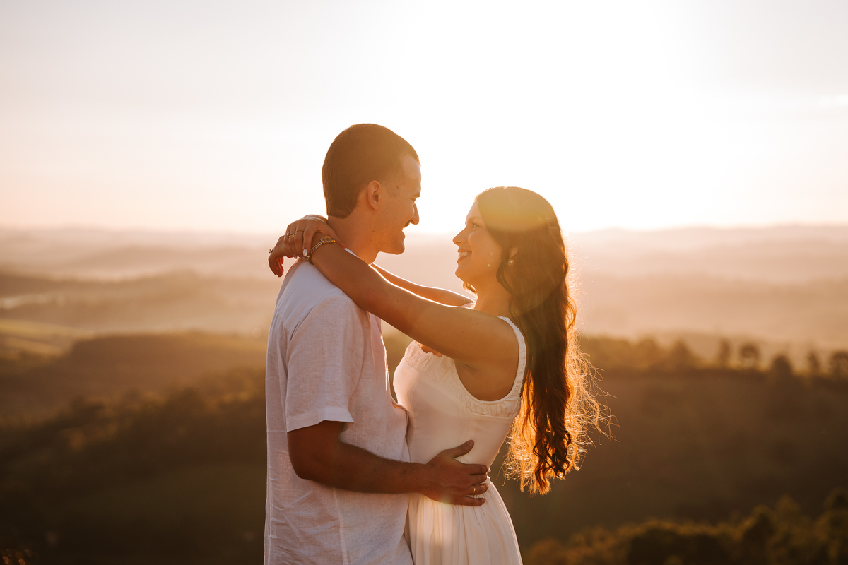 Ensaio pré-wedding com pôr do sol no alto de Pedra Bela-SP — casal trocando carinho com vista para as montanhas.