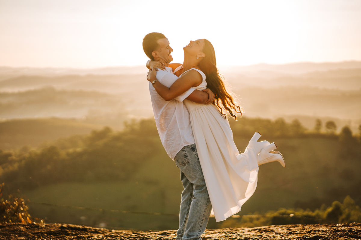 Ensaio pré-wedding com pôr do sol no alto de Pedra Bela-SP — casal trocando carinho com vista para as montanhas.