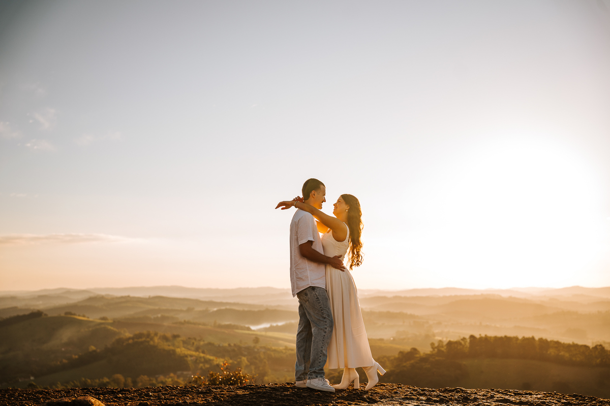 Ensaio pré-wedding com pôr do sol no alto de Pedra Bela-SP — casal trocando carinho com vista para as montanhas.