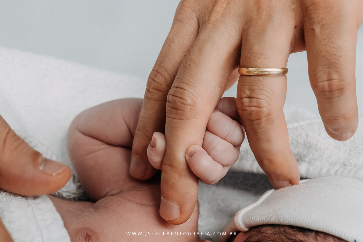 recém nascido segurando na mão do pai