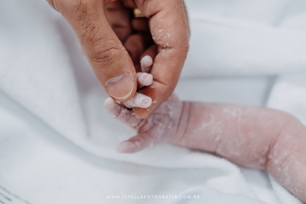 pai segurando mão do recém nascido