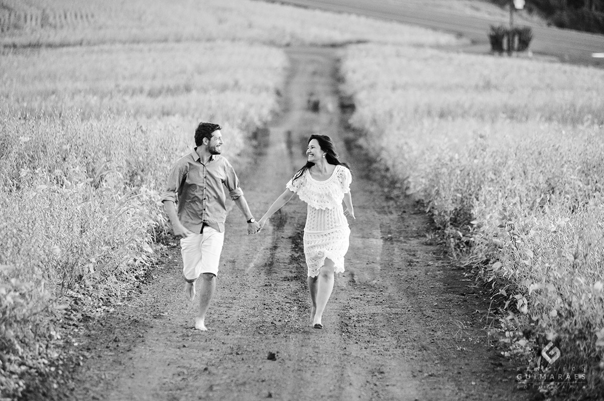 Ensaio dos noivos correndo em estrada de chão