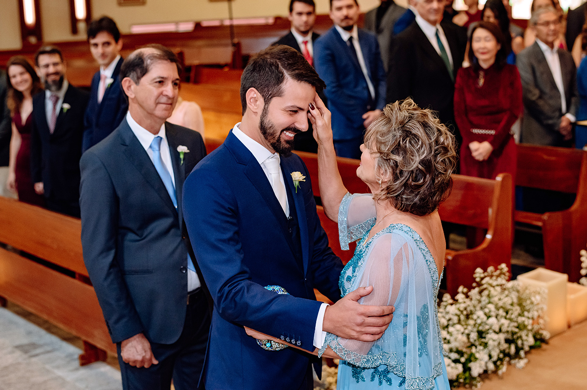 A mãe do noivo fazendo o sinal da cruz na testa do noivo