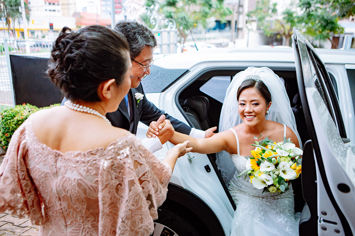 Os pais da noiva ajudando ela a sair do carro
