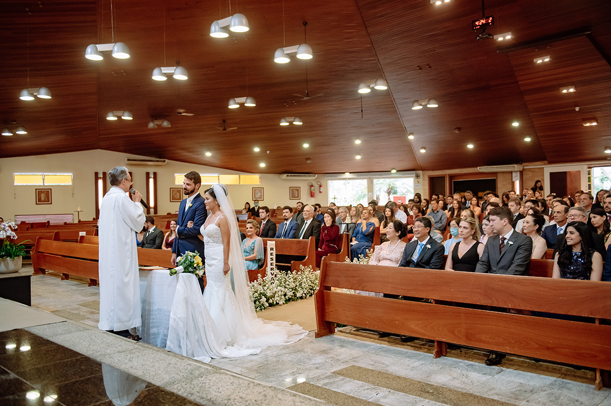 Foto aberta da cerimônia religiosa mostrando os noivos e os convidados