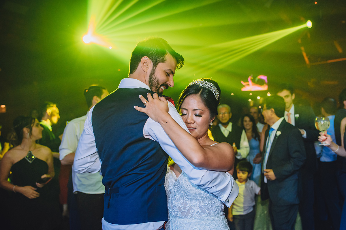 Noivos dançando na pista de dança com luzes ao fundo