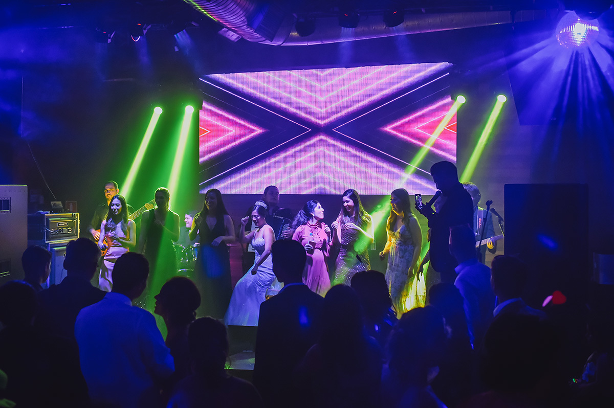 A noiva no palco cantando com as amigas