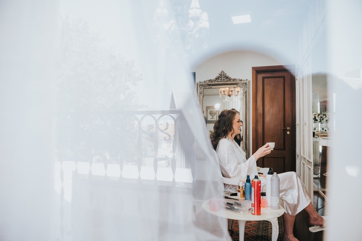 Reflexo da noiva no vidro do salão de beleza
