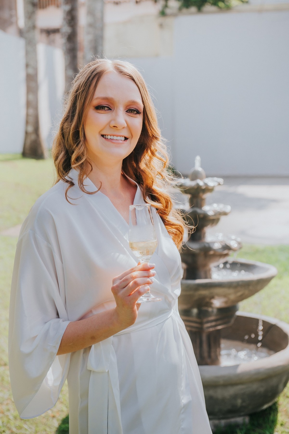 A noiva segurando uma taça de espumante perto do chafariz