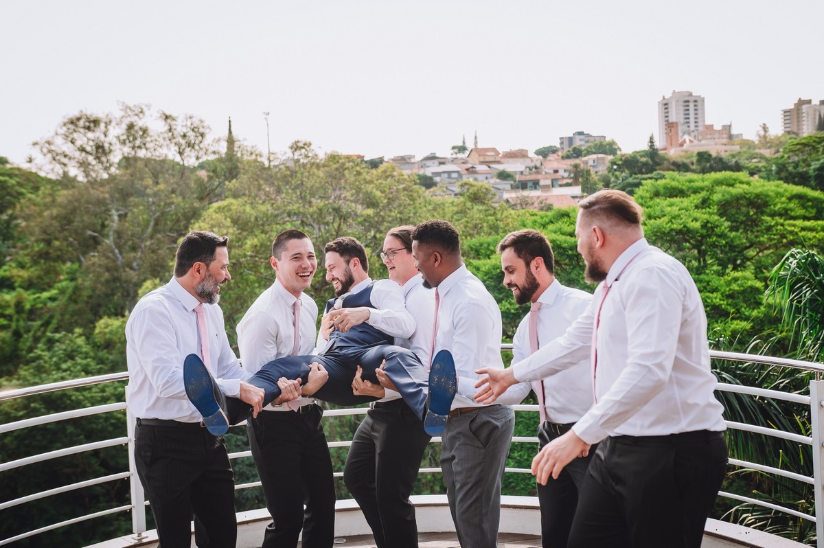 Os padrinhos segurando o noivo nos braços
