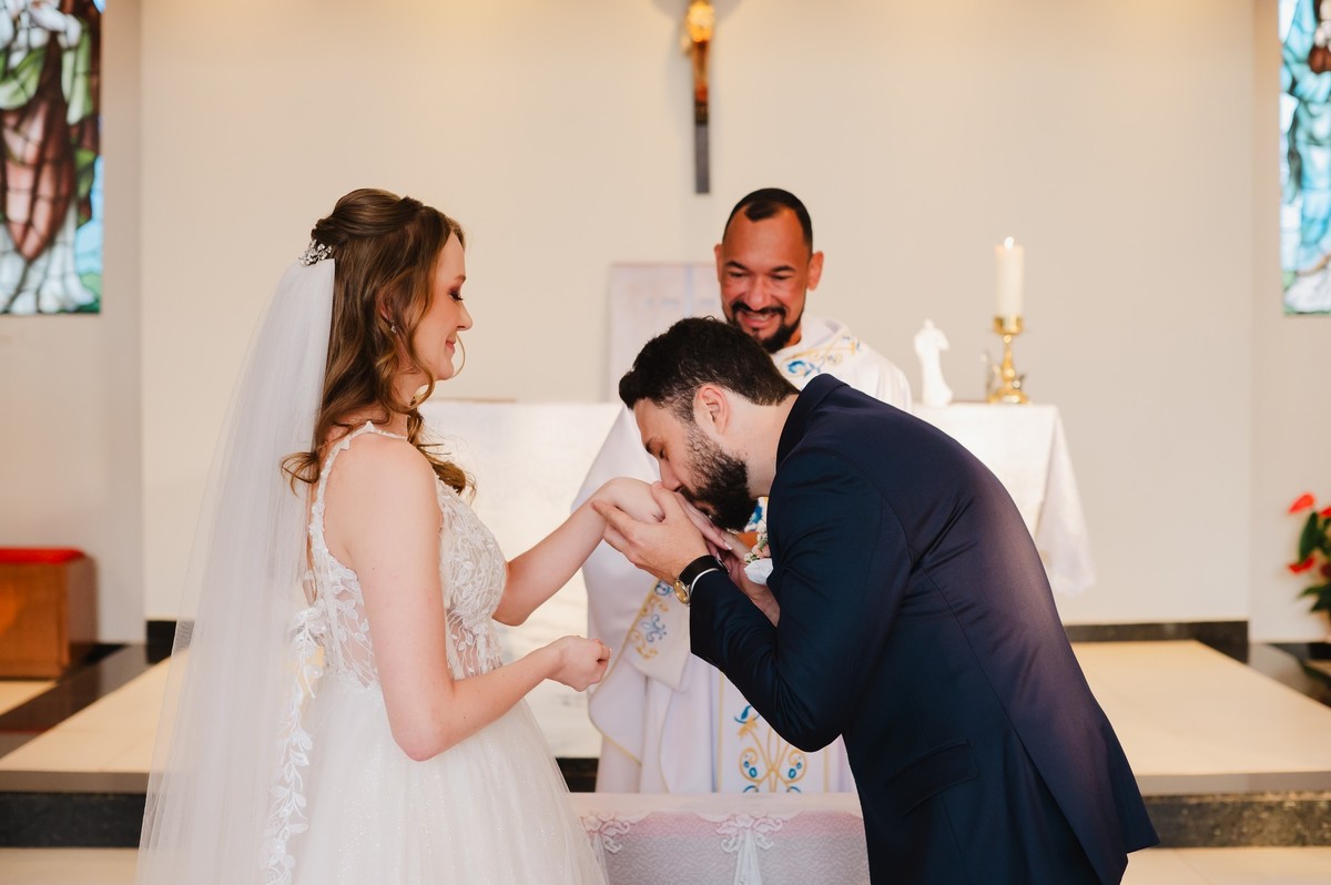 O noivo beijando a mão da noiva após colocar a aliança de casamento
