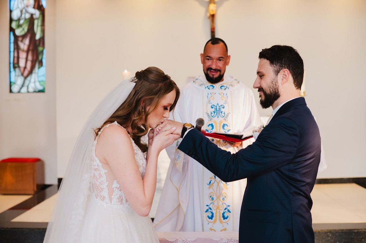 A noiva beijando a mão do noivo após colocar a aliança de casamento