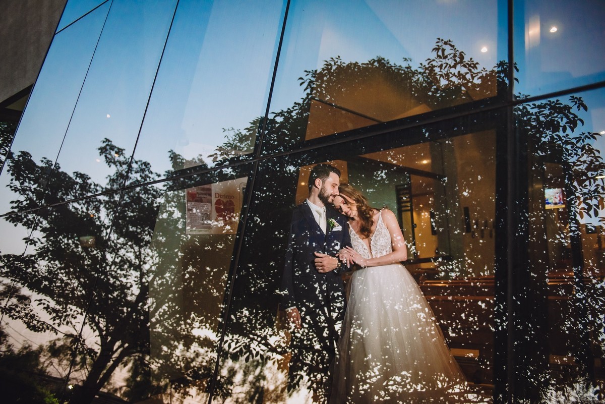 Foto dos noivos com reflexo na igreja