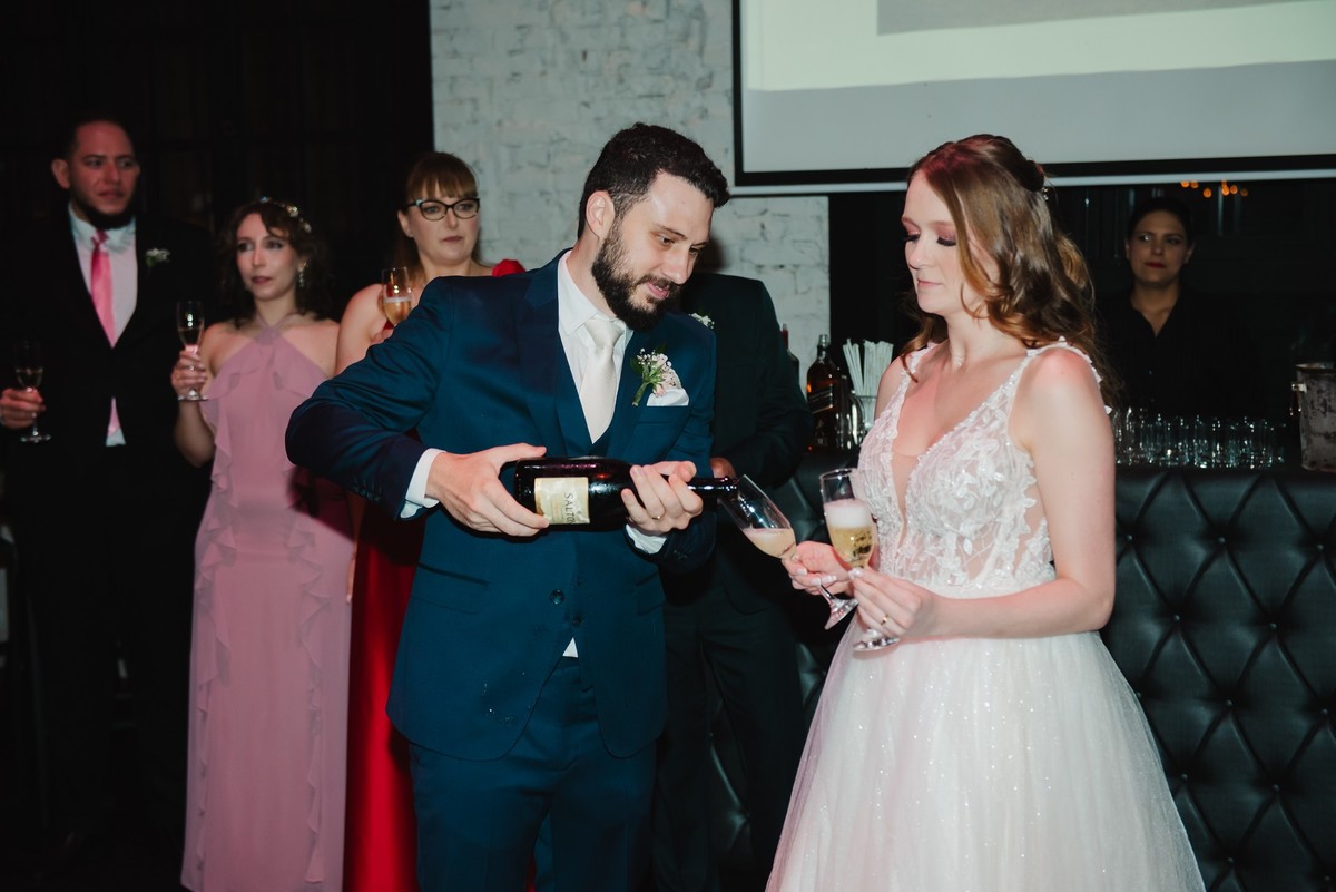 O noivo colocando o espumante nas taças