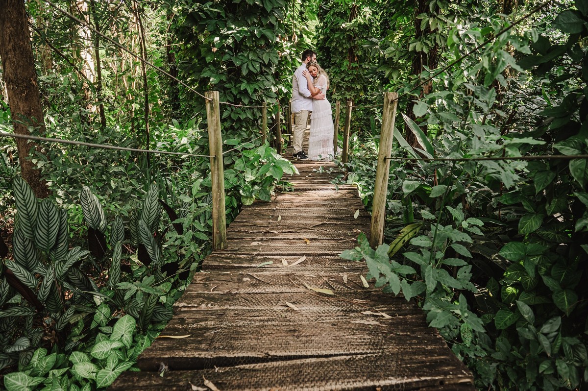Noivos abraçados em cima da ponte de madeira