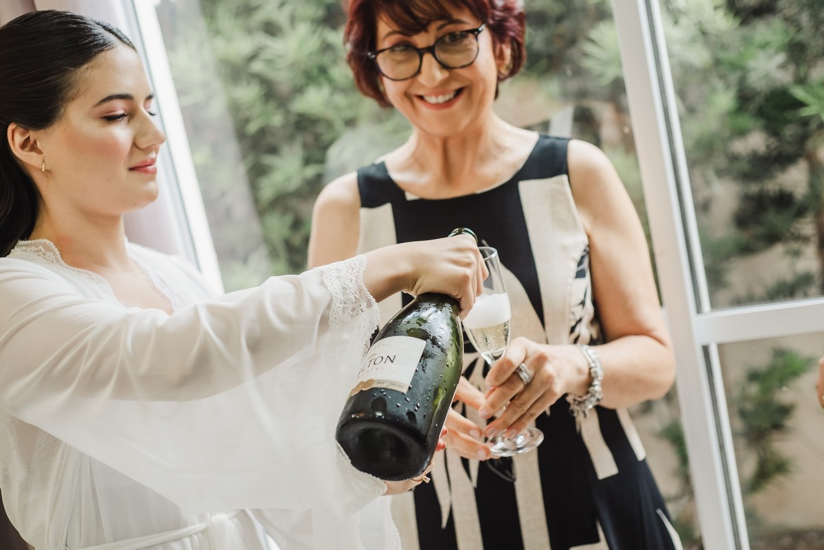 Noiva colocando o espumante nas taças das madrinhas