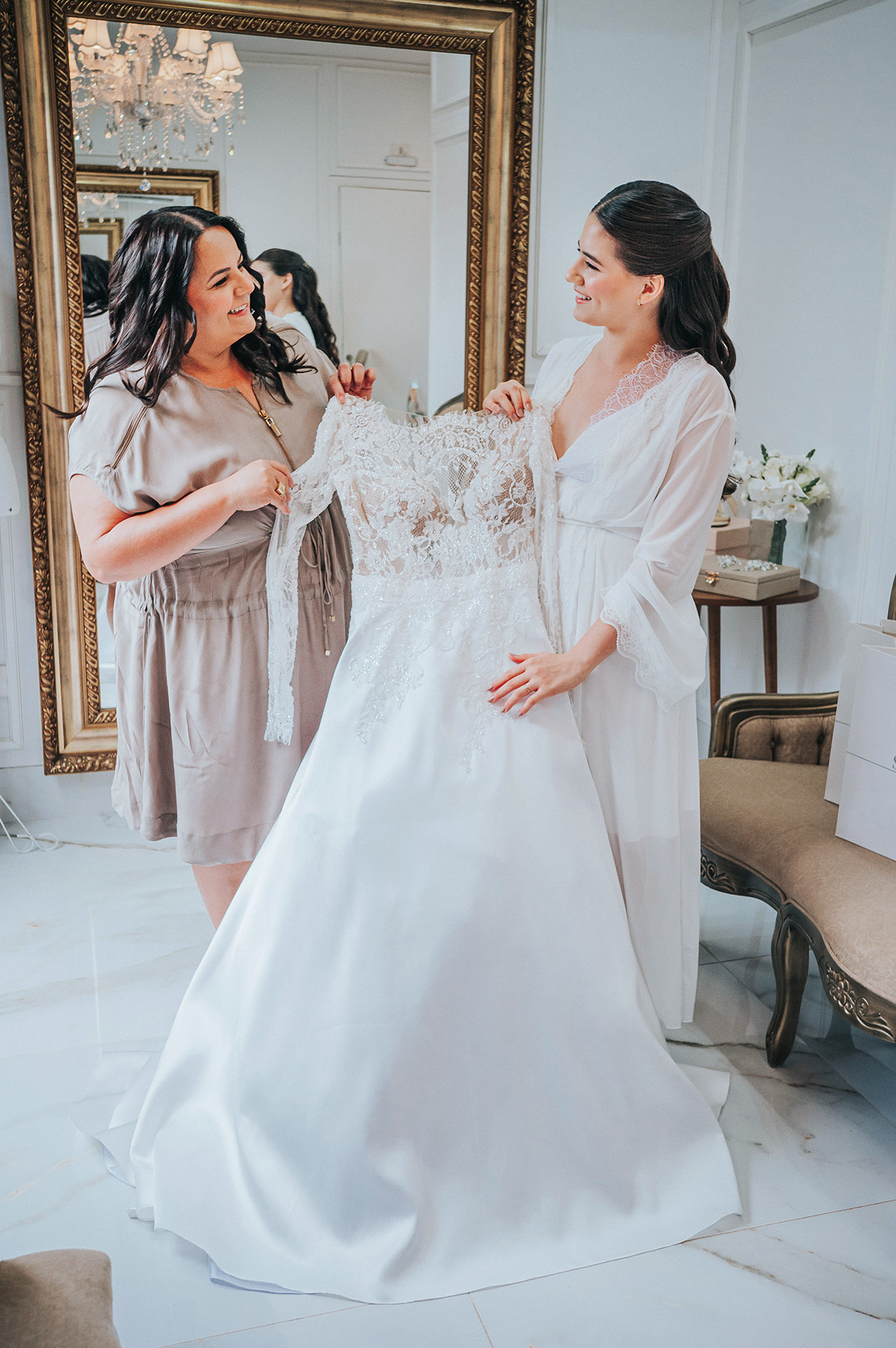 A noiva e sua mãe olhando para o vestido de noiva