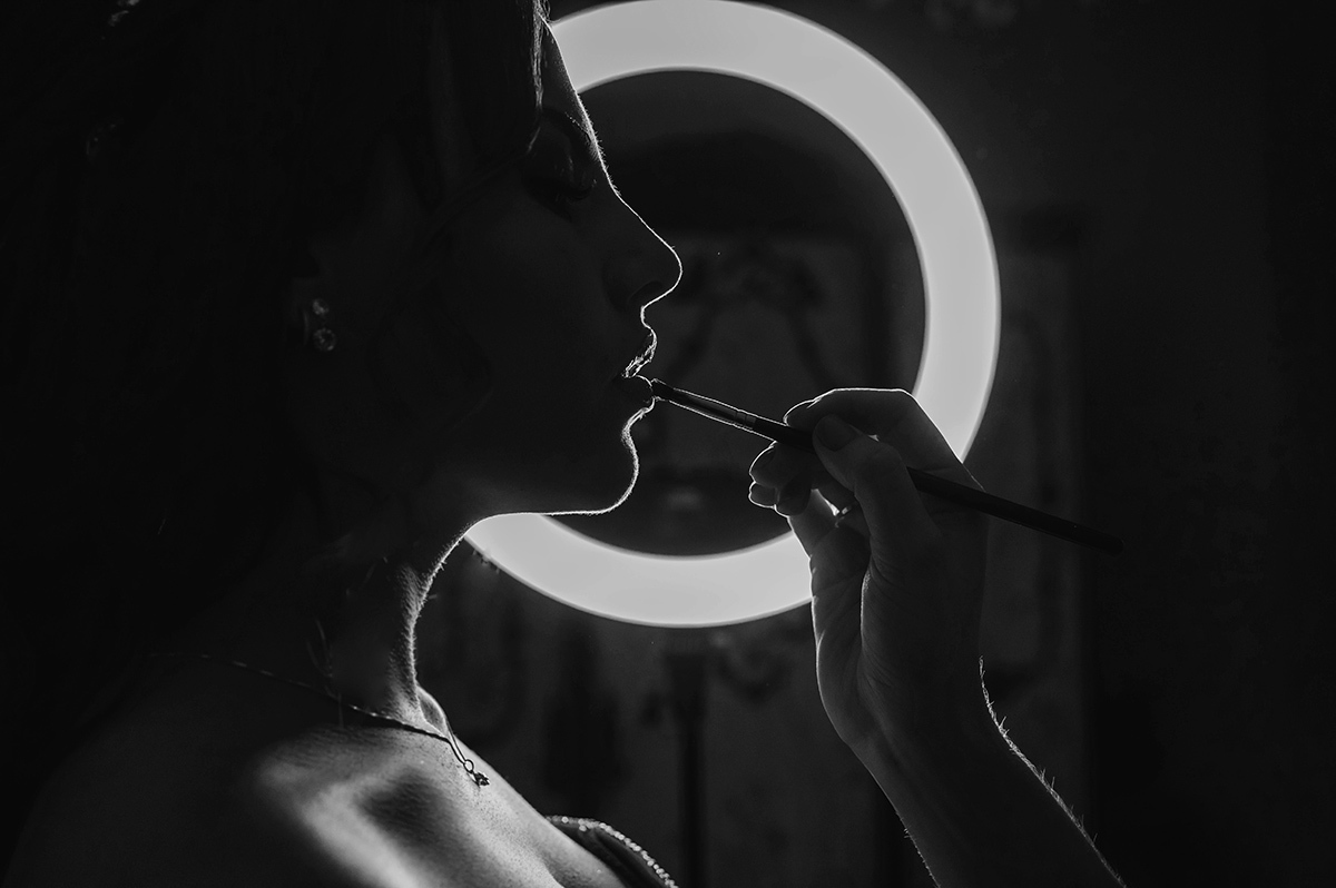 Foto de silhueta da maquiadora passando baton na debutante