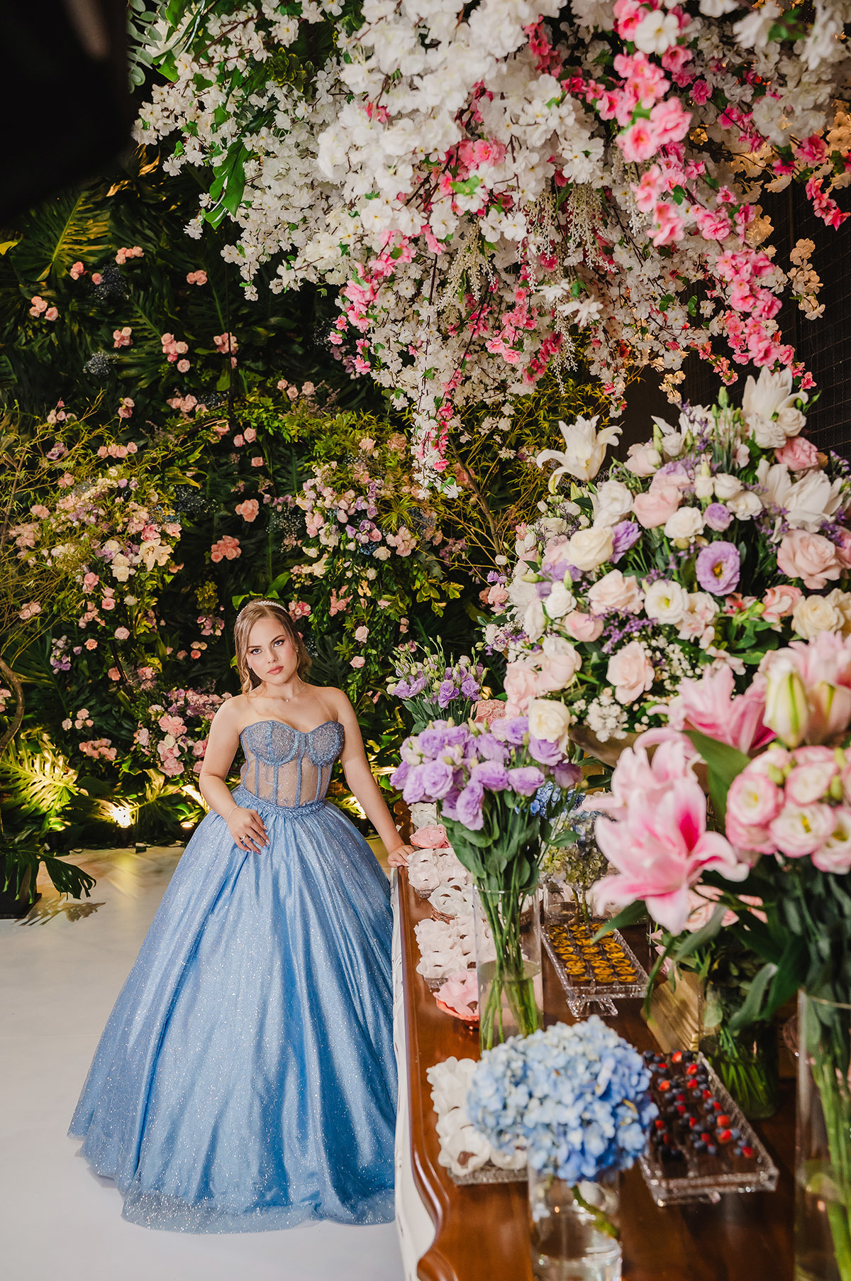 Muitas flores em primeiro plano, com a aniversariante de 15 anos no segundo plano