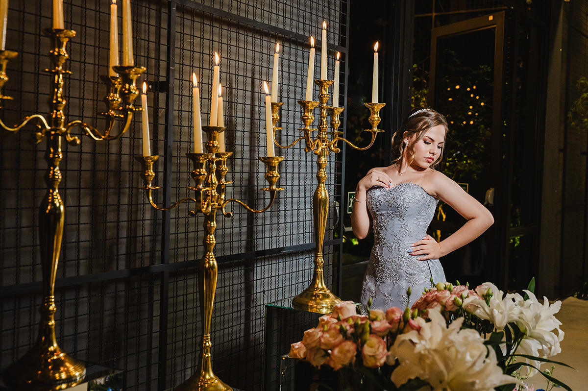 A debutante posando para as fotos do lado da sua decoração com velas