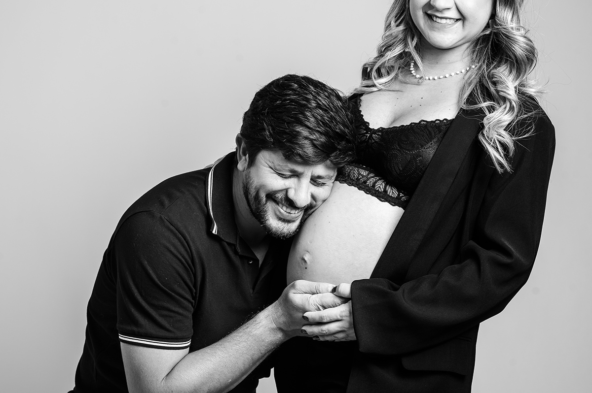 o pai com o ouvido na barriga da esposa ouvindo o bebê