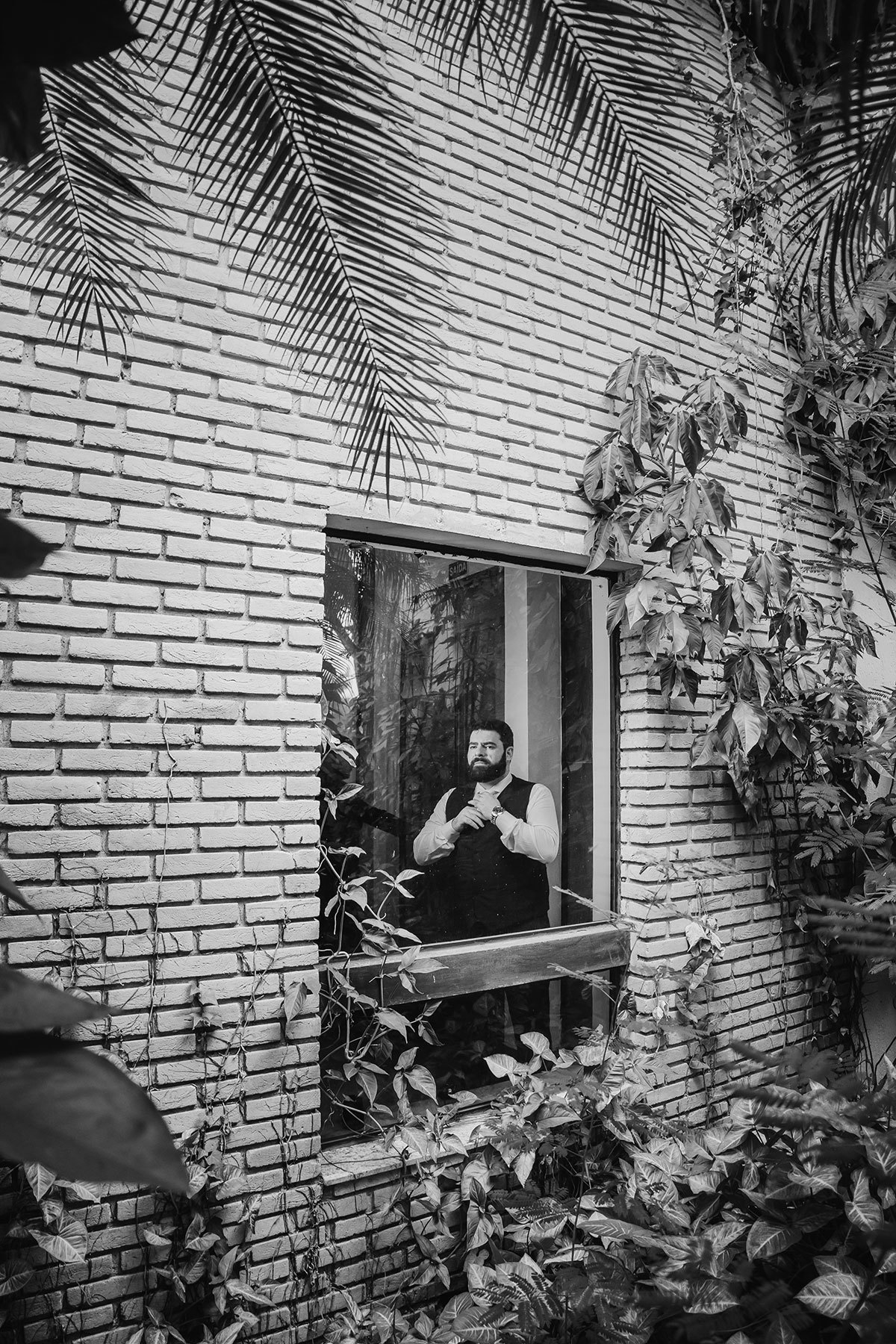 Foto do noivo de fora da janela, arrumando a gravata