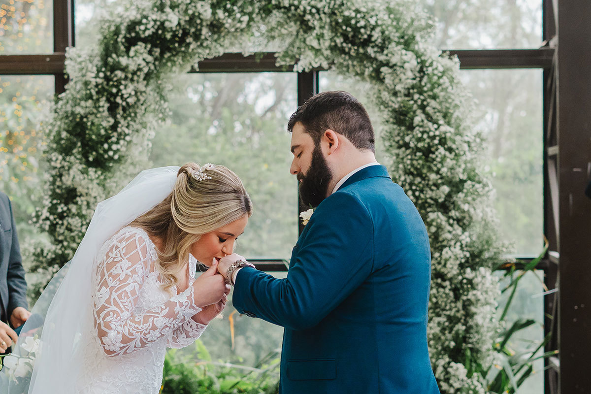 a noiva beijando a mão da aliança do noivo