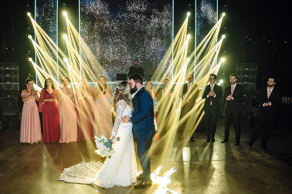 fotos dos noivos na pista de dança com luzes amarelas atrás