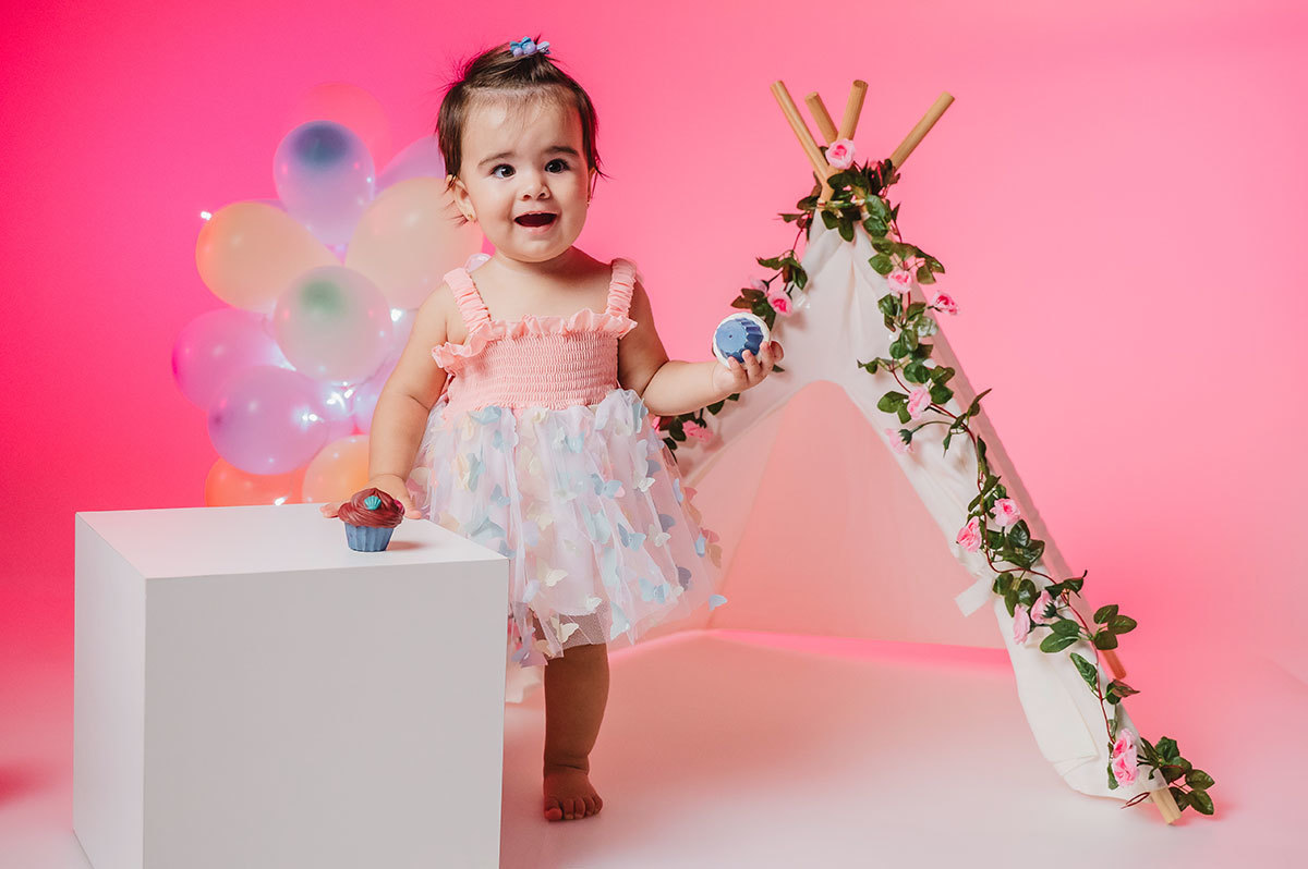 Ensaio da Lara em pé segurando um cupcake de brincadeira