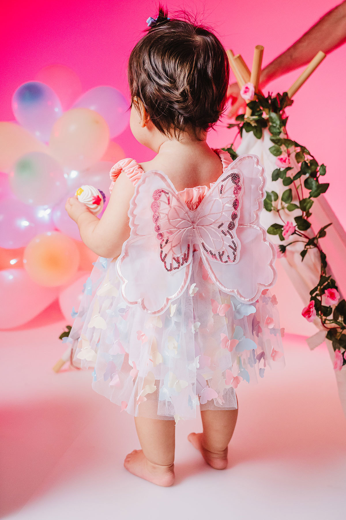 Fato da Lara de costas mostrando a fantasia de asas de borboletas 